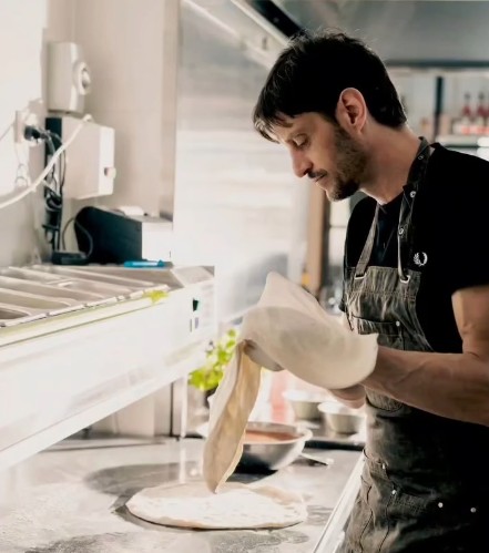 Chef hand-stretching pizza dough on the bench in the kitchen at The Code Pizza Bar